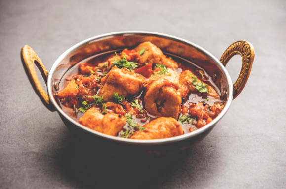 Spicy Indian chicken curry garnished with fresh cilantro in a traditional metal kadai bowl.
