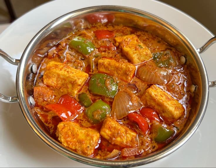 Paneer cubes, green and red bell peppers, and onions in a rich, spicy orange gravy.